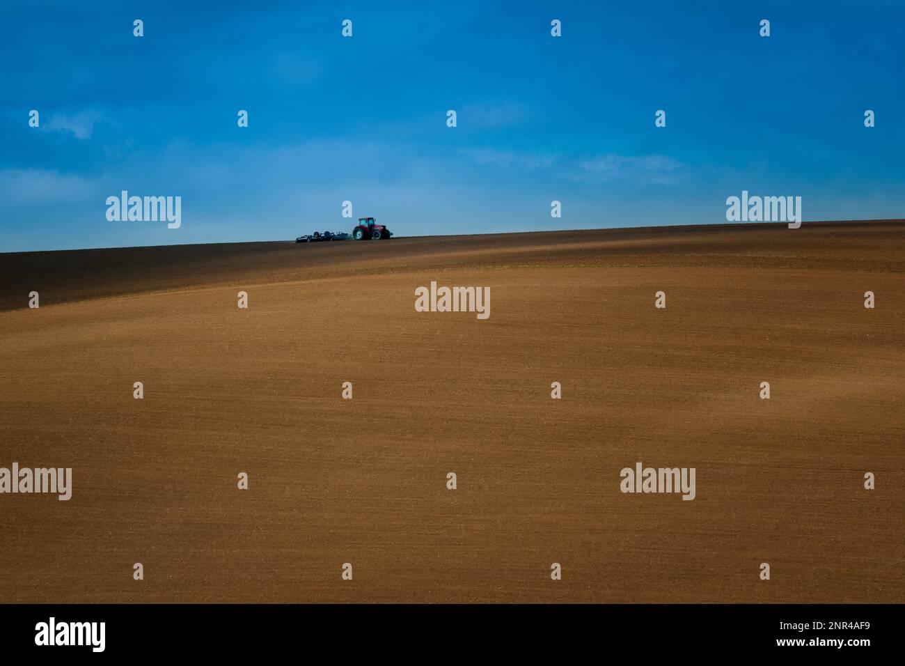 Arbeiten mit einem landwirtschaftlichen Traktor auf mährischen Feldern. Ein wunderbarer blauer Himmel. Tschechische republik, Mährisch, Tschechische republik Stockfoto