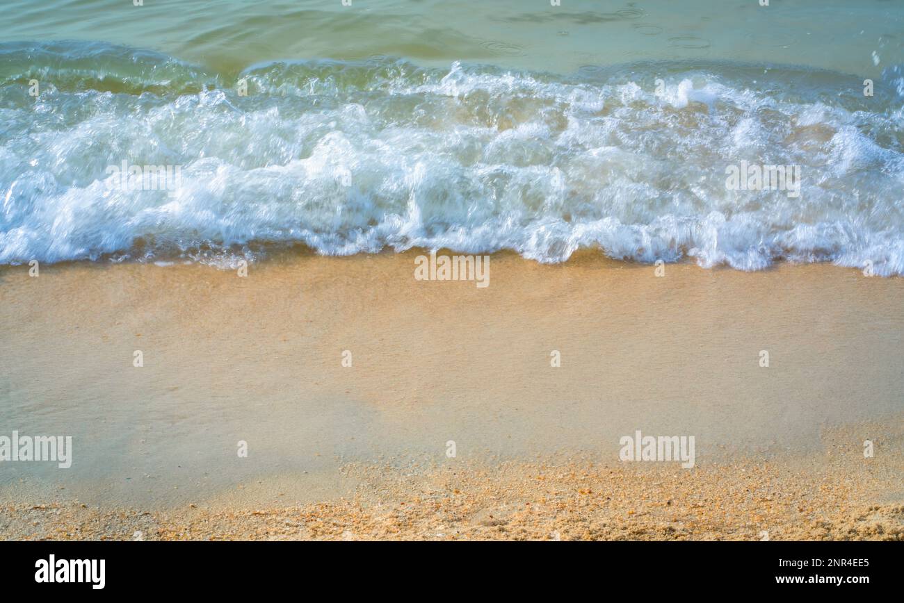 Meereswelle mit Schaum am sauberen Sandstrand. Naturhintergrundkonzept. Stockfoto