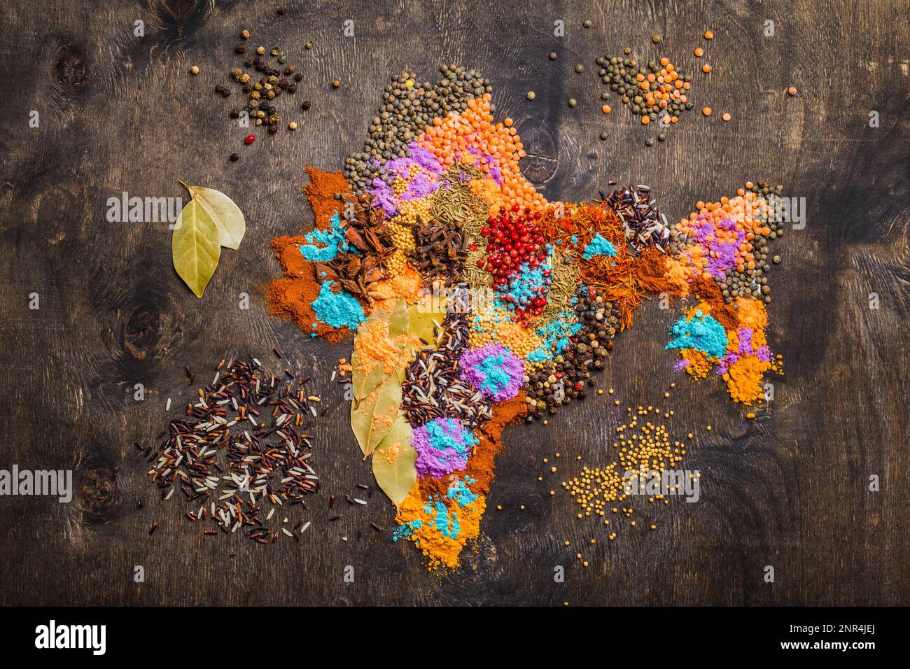 Karte von Indien aus verschiedenen traditionellen indischen Gewürzen, Reis, Linsen und Puder in den Farben Holi auf dunklem Holzhintergrund, Draufsicht. Gewürze und Stockfoto