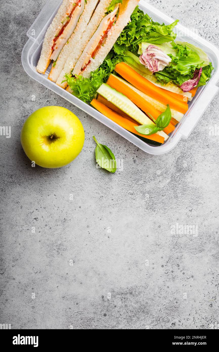 Eine Lunchbox für Büro oder Schule mit gesundem Essen: Sandwiches, Karotten- und Gurkenstangen, Salat, Apfel. Zubereitung und Verpackung des Essens für den Support Stockfoto