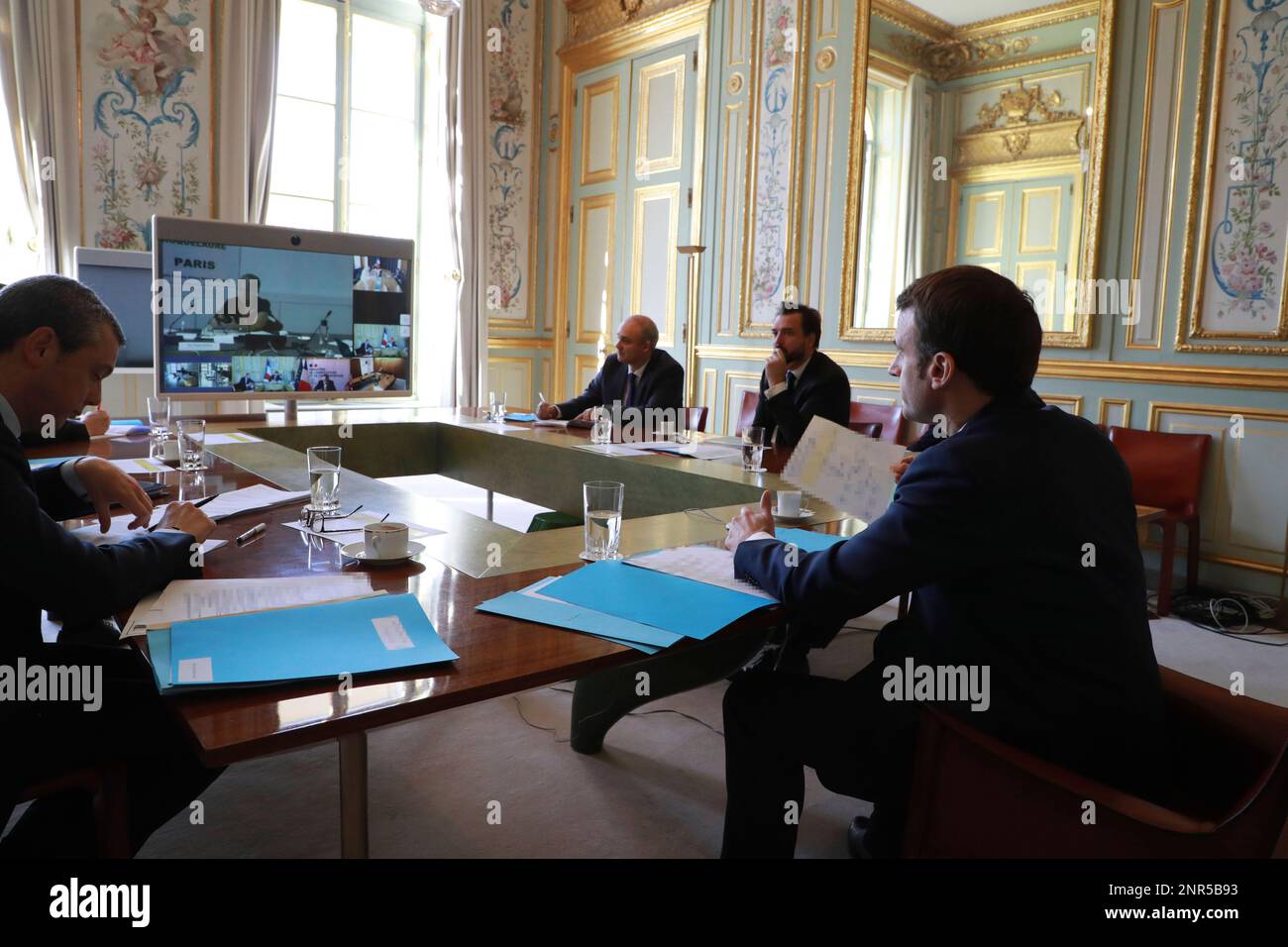 French president Emmanuel Macron, right, general secretary of the presidency Alexis Kohler, left, and other advisers take part to a videoconference of the "economic task force with French economic leaders and members of the governement about coronavirus (COVID-19) epidemic at the Elysee Palace in Paris on March 19, 2020. For most people, the new coronavirus causes only mild or moderate symptoms. For some it can cause more severe illness. (Ludovic Marin / POOL via AP) Stockfoto