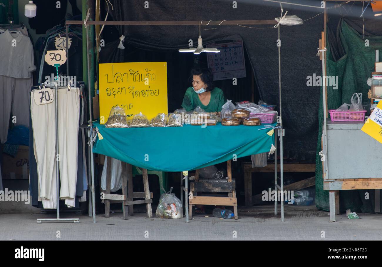 SAMUT PRAKAN, THAILAND, FEBRUAR 13 2023, Ein Verkäufer auf dem Markt bietet Minnow und ein Produkt aus getrockneter Mango an Stockfoto