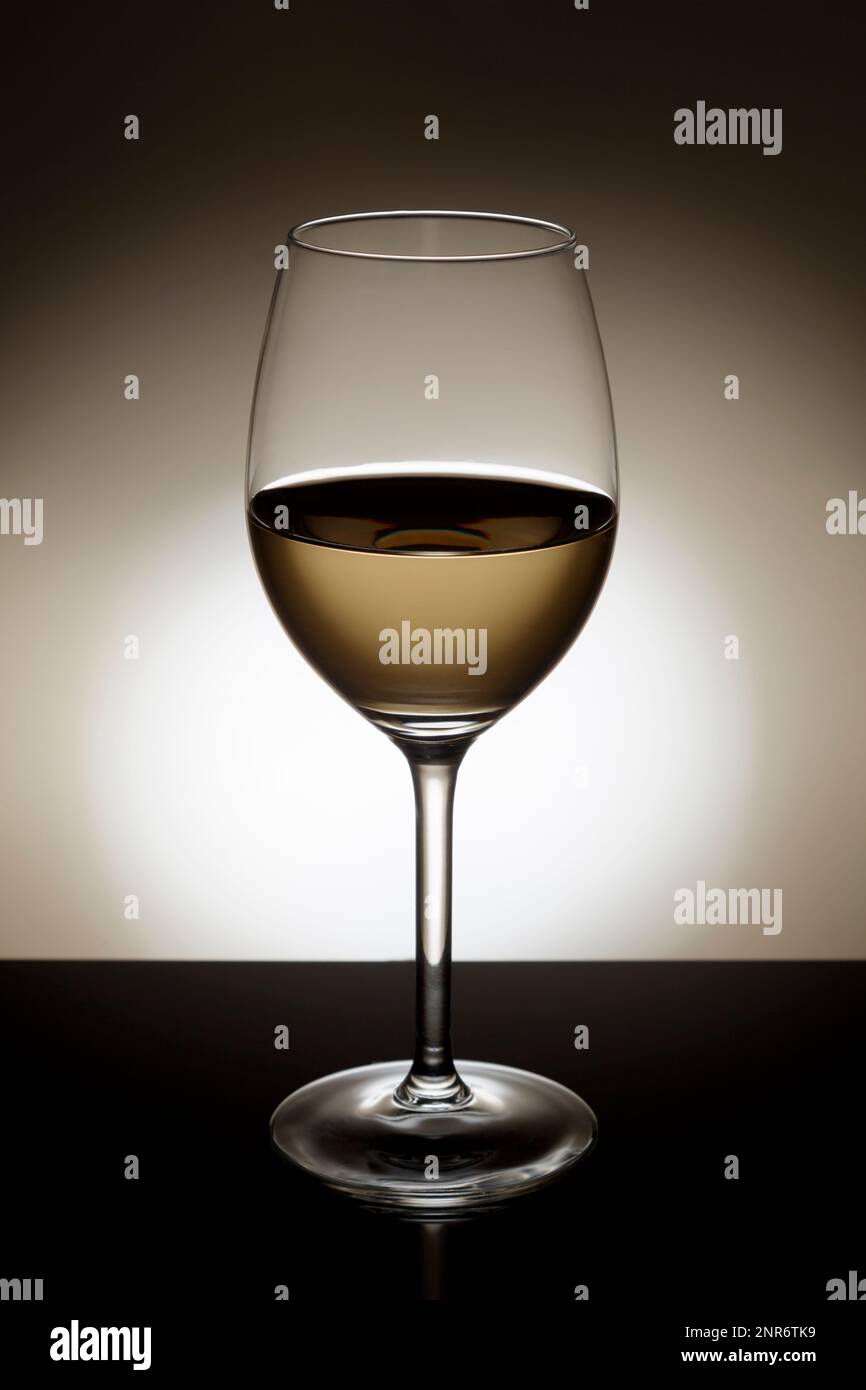 Weißwein in einem Glas mit Hintergrundbeleuchtung. Stockfoto