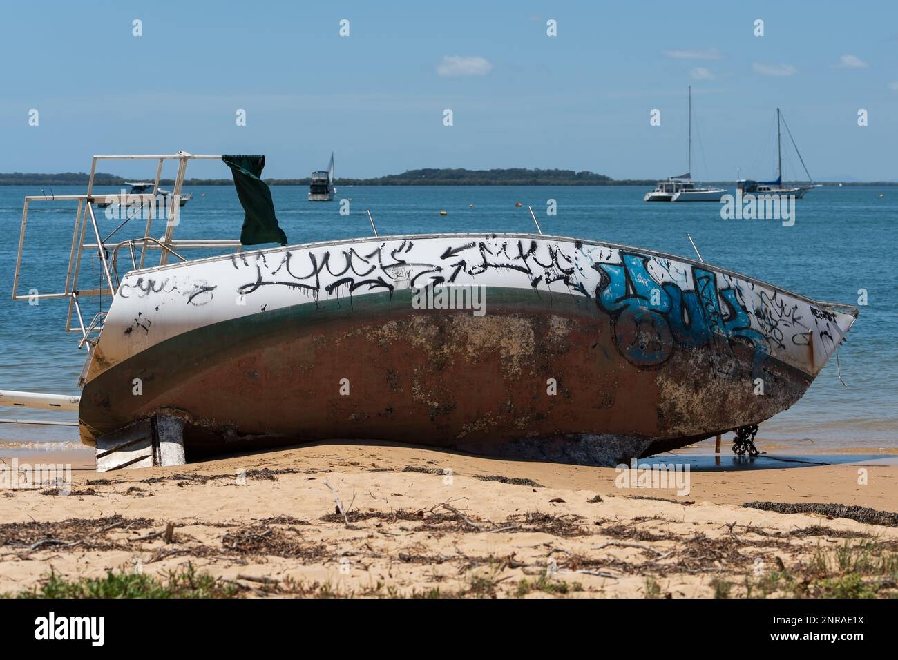 Am Sandstrand liegendes Boot mit Graffiti-überdachtem Rumpf. Stockfoto