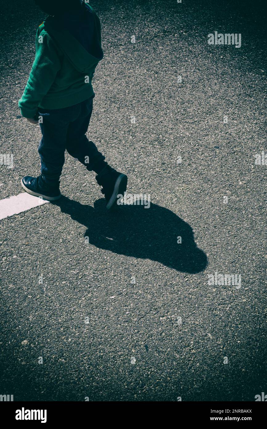 Ein kleiner Junge, der auf der Straße läuft Stockfoto