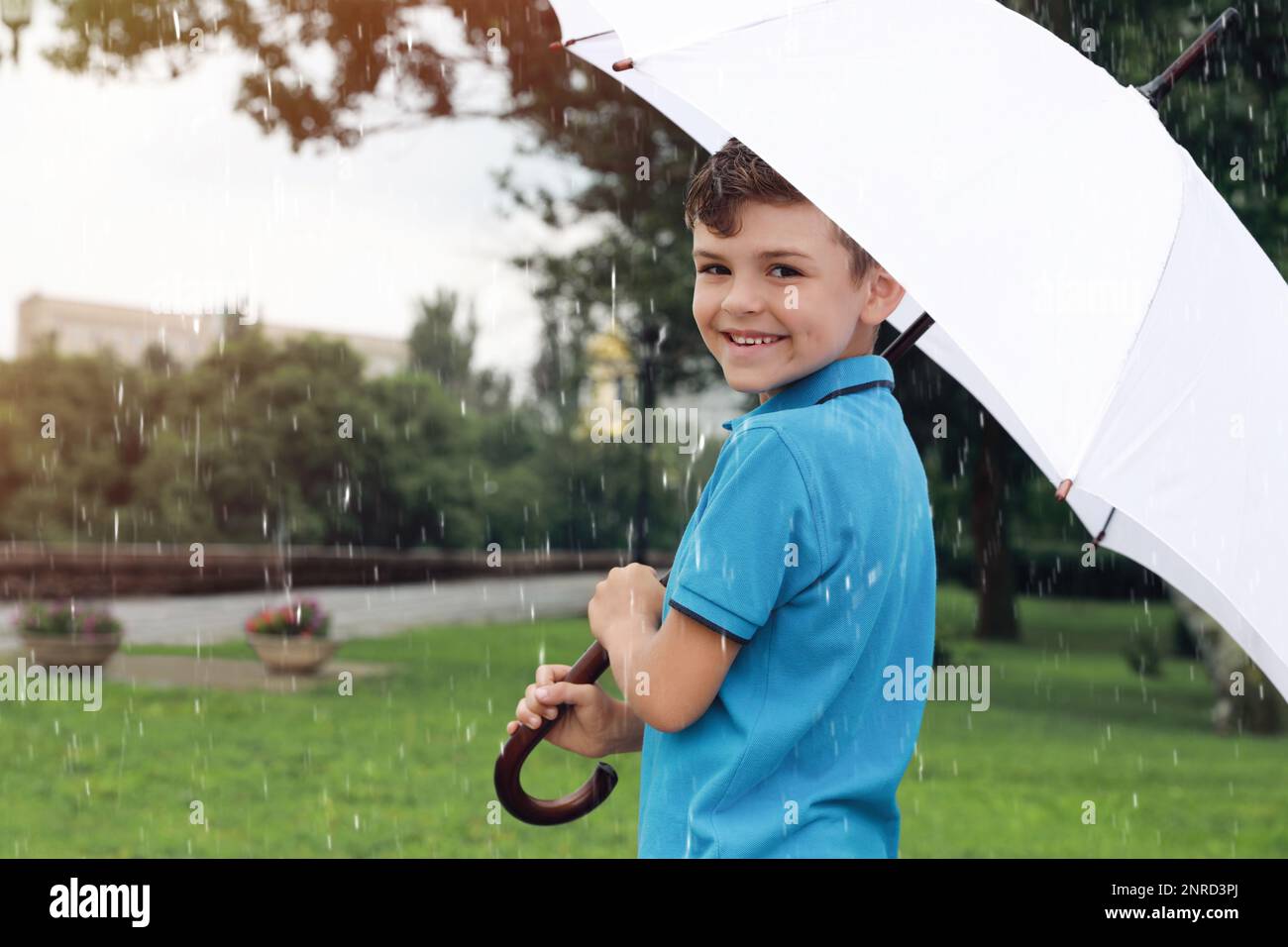 Ein kleiner Junge mit Regenschirm, der im Park unter Regen läuft  Stockfotografie - Alamy