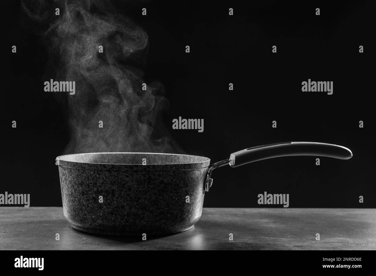 Dampftopf auf grauem Tisch vor dunklem Hintergrund Stockfoto