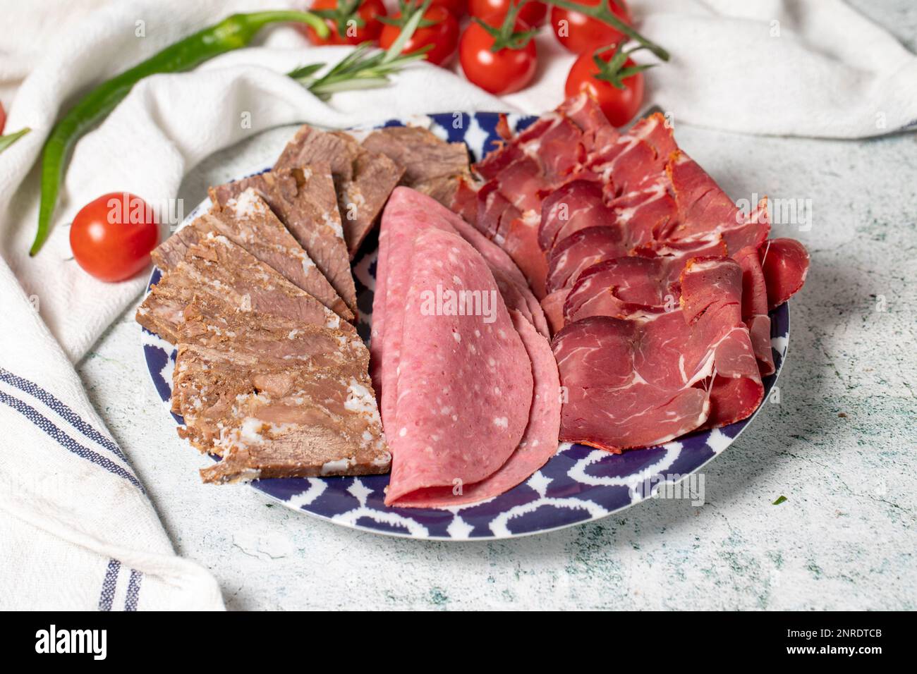 Kaltgeräucherter Fleischteller, Antipasto-Teller. Gebratenes Fleisch, Salami und Speck auf grauem Hintergrund Stockfoto