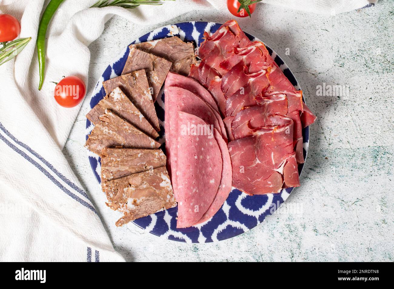 Kaltgeräucherter Fleischteller, Antipasto-Teller. Gebratenes Fleisch, Salami und Speck auf grauem Hintergrund. Draufsicht Stockfoto