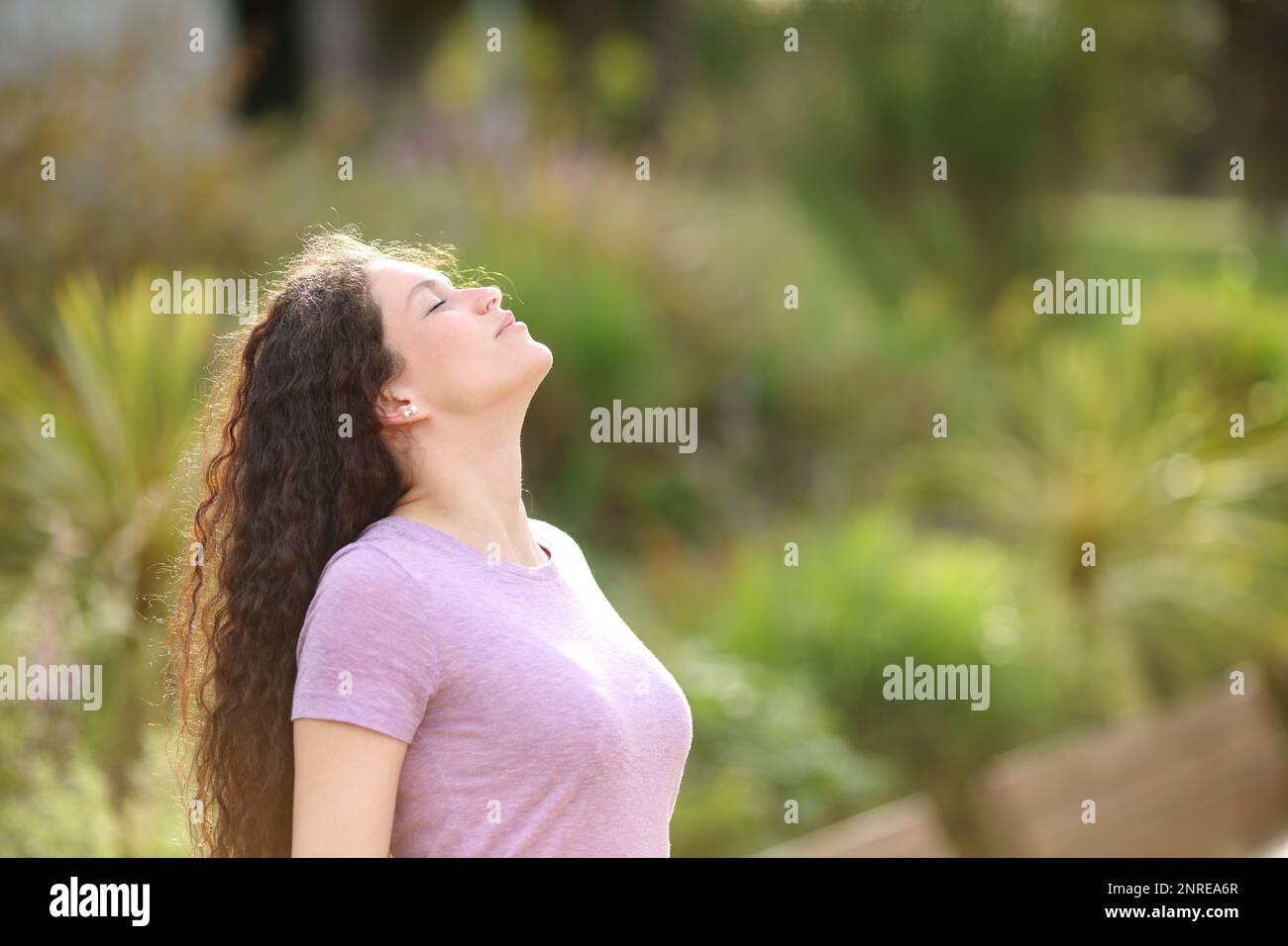 Eine Frau, die frische Luft atmet und in einem grünen Park steht Stockfoto