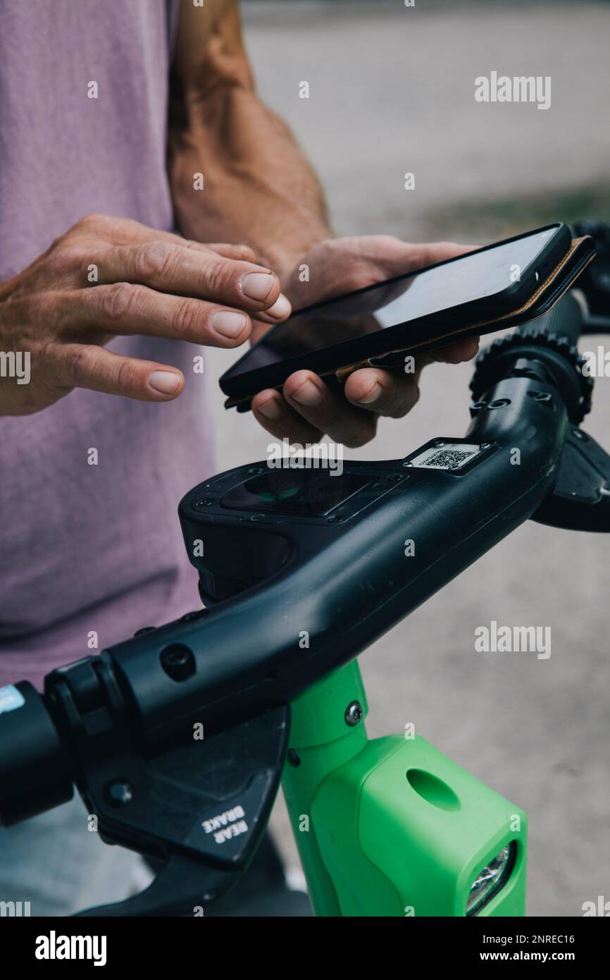 Nahaufnahme der Hände mit Smart Phon zum Entriegeln des elektrischen Rollers Stockfoto