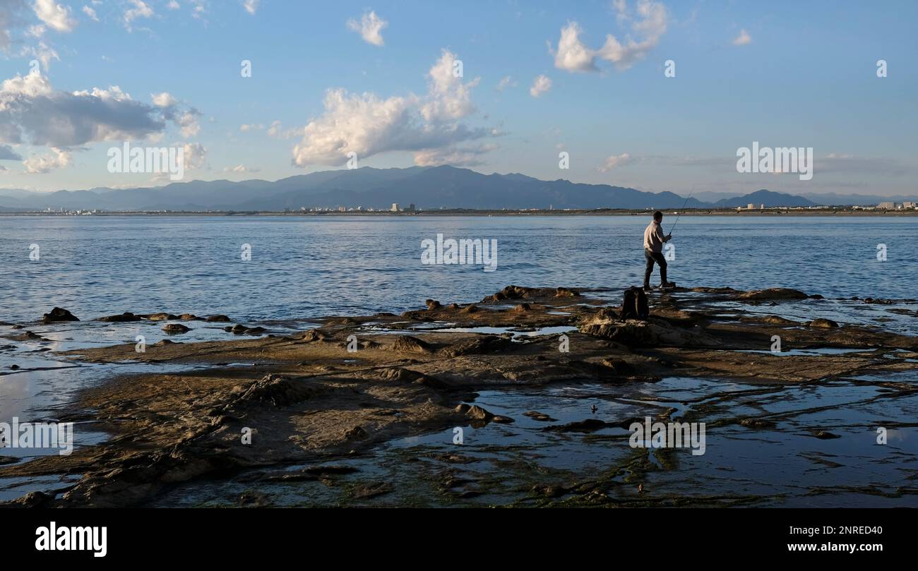 Spektakuläre Landschaften an der Küste von Enoshima, Japan, mit einem einzigen Fischer am Rand des Wassers Stockfoto