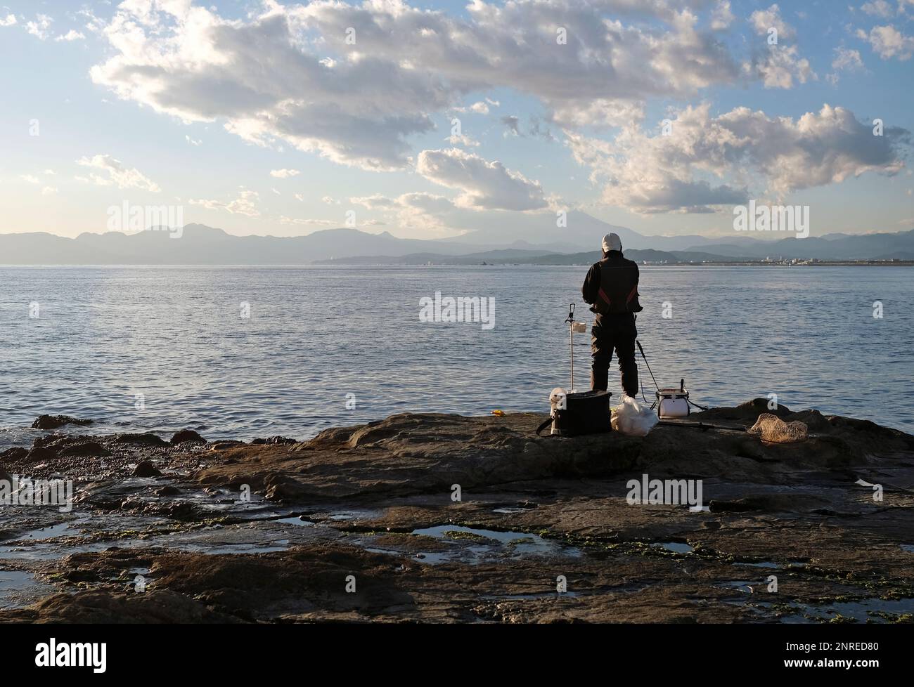 Spektakuläre Landschaften an der Küste von Enoshima, Japan, mit einem einzigen Fischer am Rand des Wassers Stockfoto