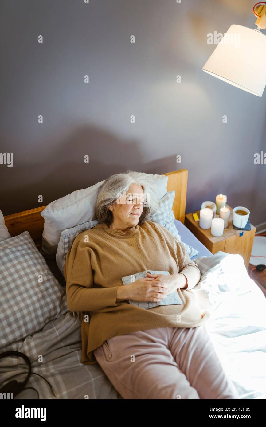 Blick auf Seniorin, die schläft, während sie zu Hause im Bett liegt Stockfoto