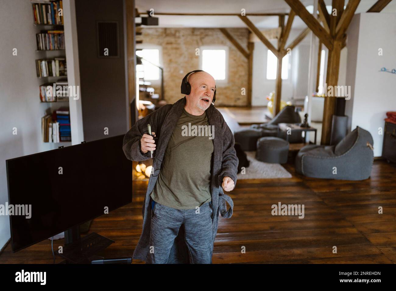 Sorgenfreier Seniorenmann, der zu Hause tanzt und dabei Musik hört Stockfoto