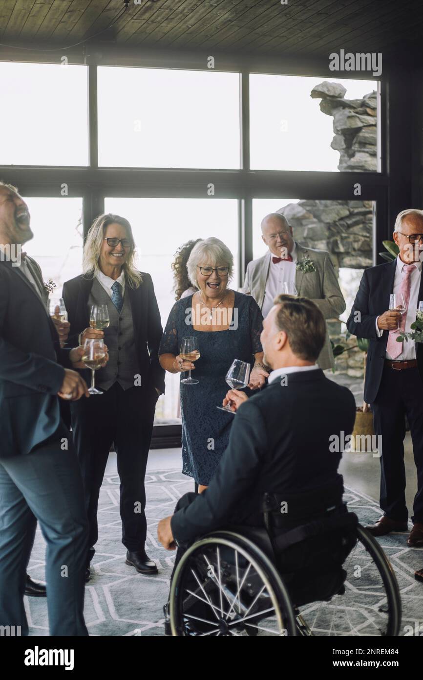 Männliche und weibliche Gäste aus verschiedenen Rassen, die bei der Hochzeitszeremonie einen Drink zu sich nehmen Stockfoto