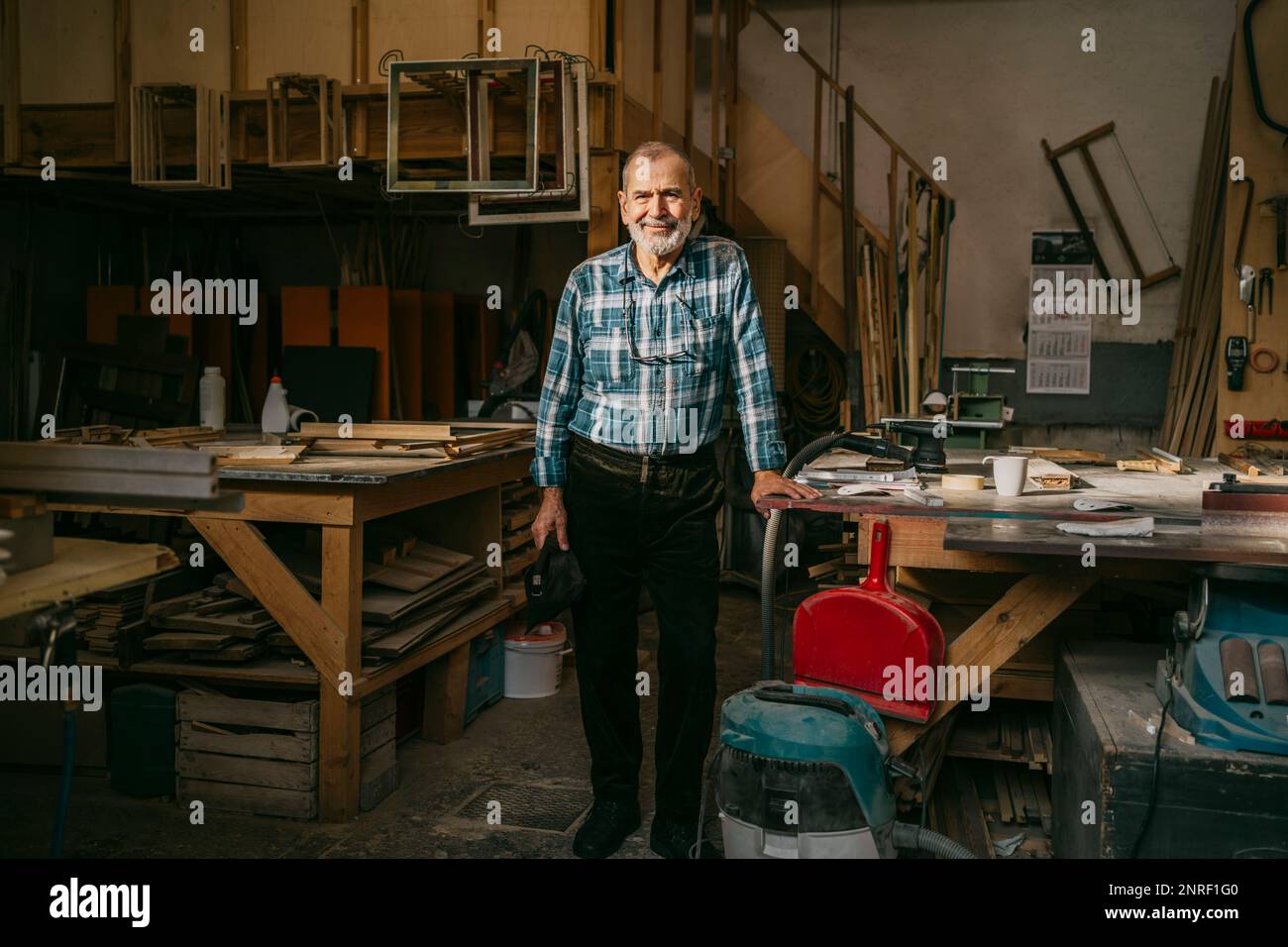 Ein erfahrener Handwerker steht neben der Werkbank in der Tischlerwerkstatt Stockfoto