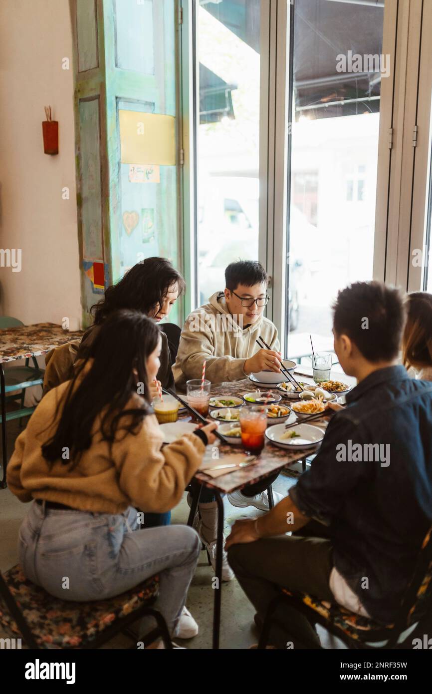 Männliche und weibliche Freunde essen zusammen im Restaurant zu Mittag Stockfoto