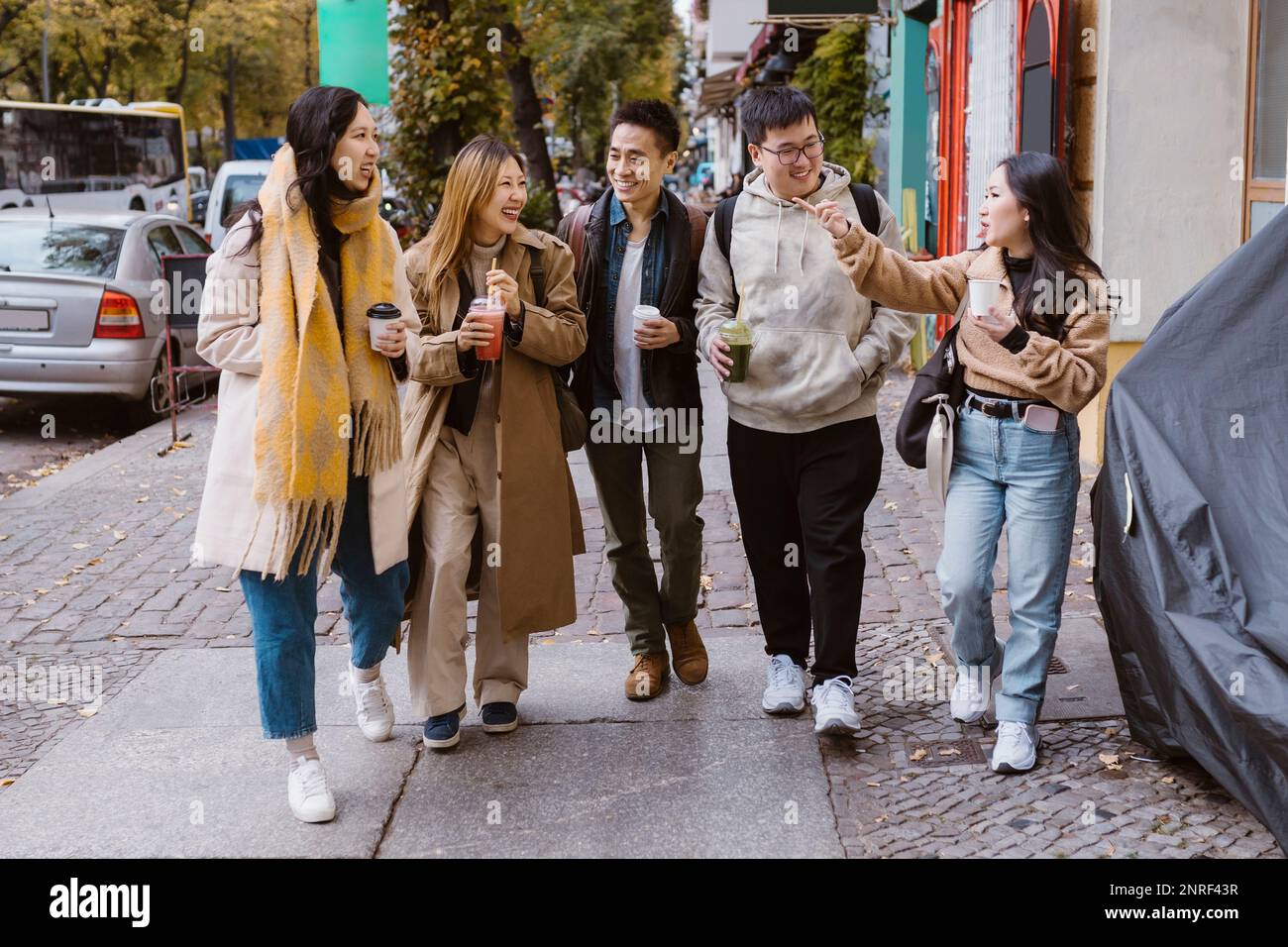 Multirassische männliche und weibliche Freunde kommunizieren, während sie auf dem Bürgersteig gehen Stockfoto
