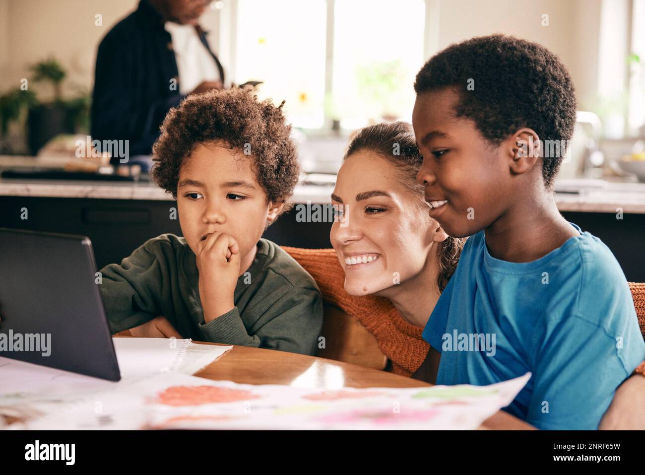 Glückliche Mutter und Söhne, die sich zu Hause ein digitales Tablet ansehen Stockfoto