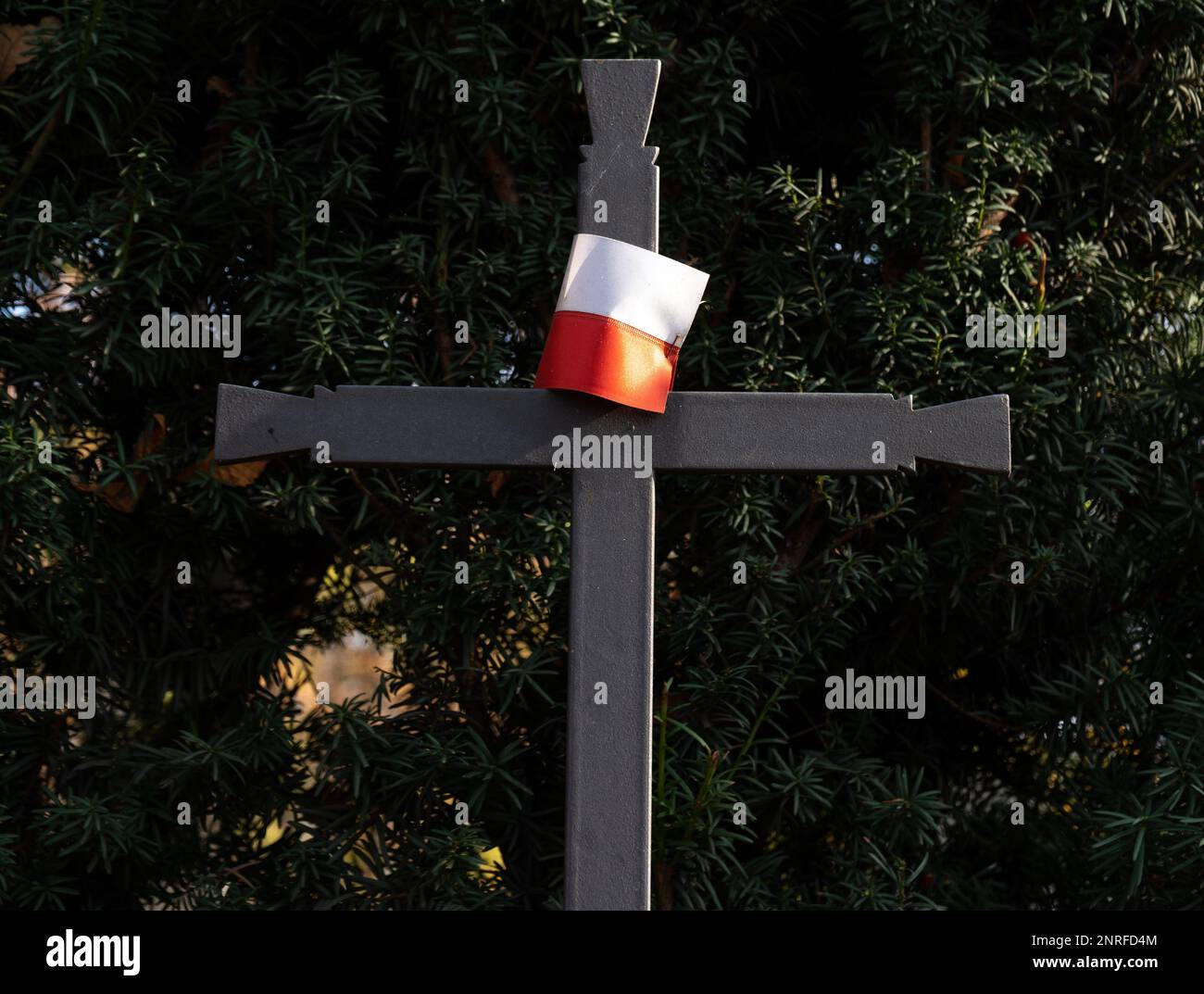 Heiliges Kreuz mit polnischer Flagge auf dem Friedhofsgrab. Memorial Day, kleine Flagge Polens auf einem Metallkreuz auf dem Militärfriedhof, zum Gedenken an gefallene Soldaten. Stockfoto
