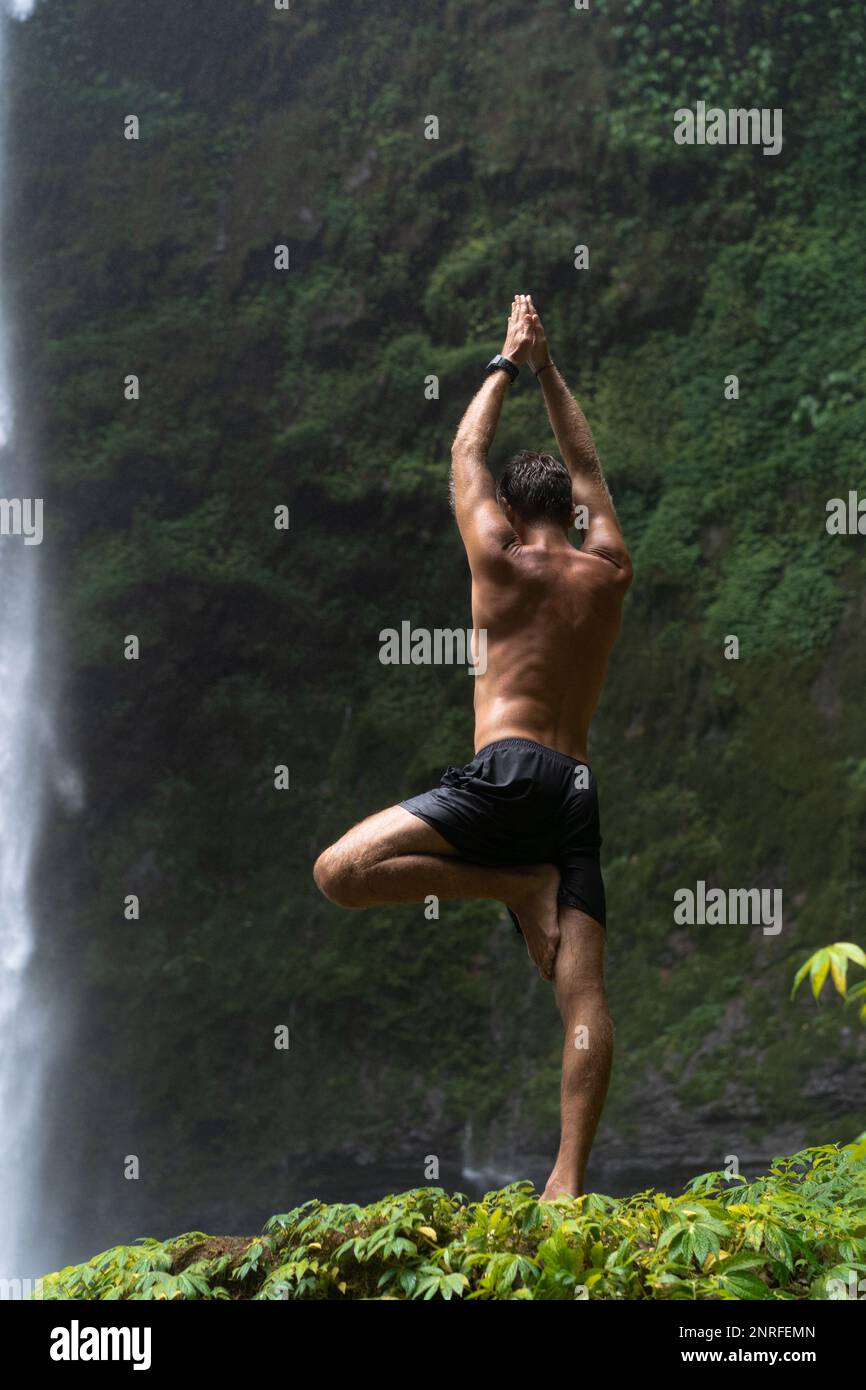 Vrikshasana-Baum-Pose aus Yoga durch Männersilhouette im Dschungel. Stockfoto