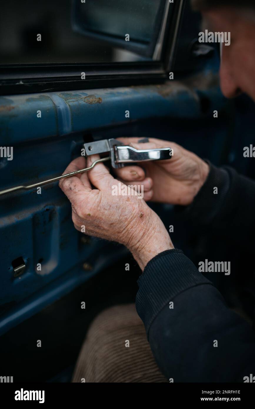 Der alte Techniker, der die Autotür beim Schließen zu Hause installiert Stockfoto
