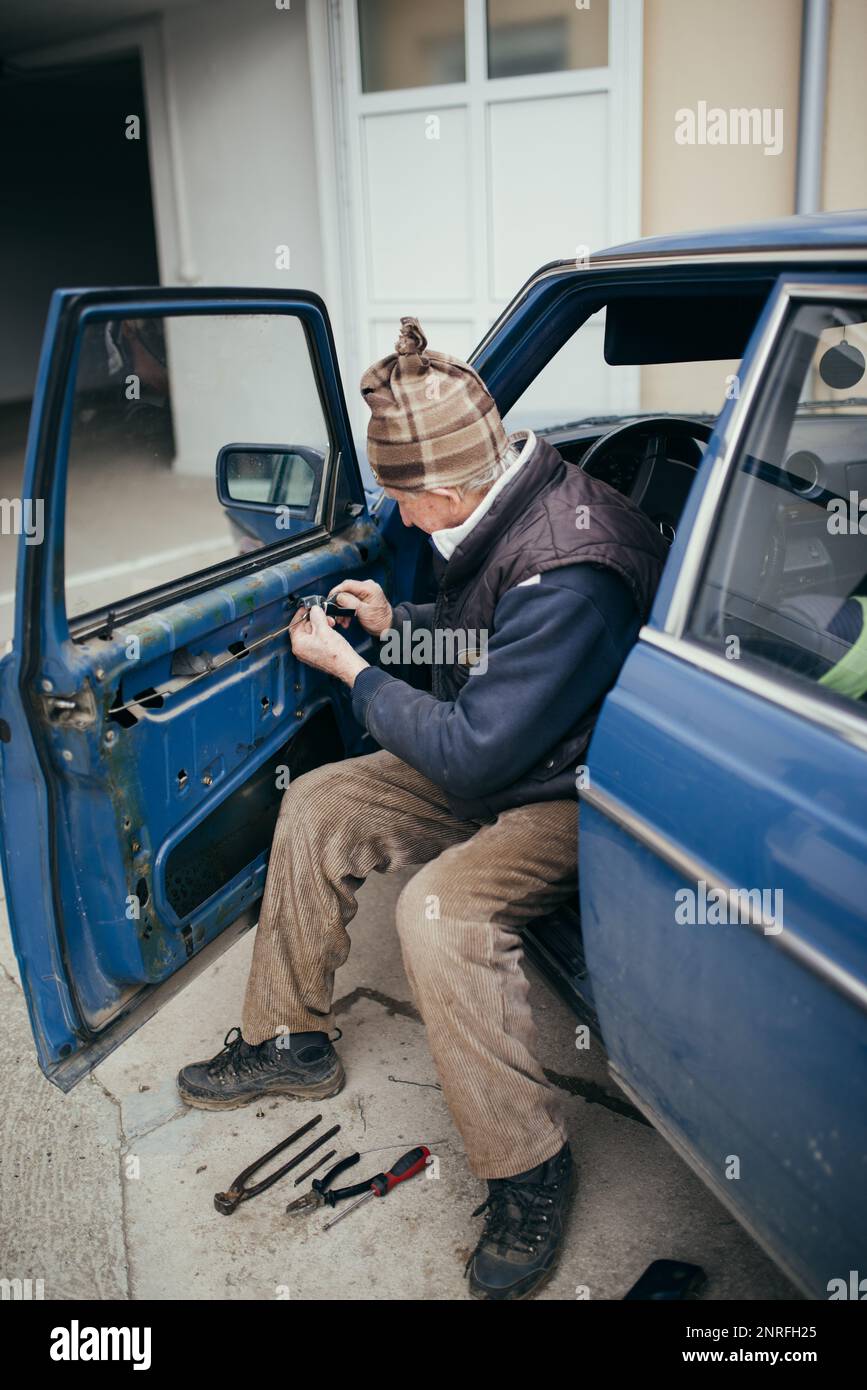 Der alte Techniker, der die Autotür beim Schließen zu Hause installiert Stockfoto