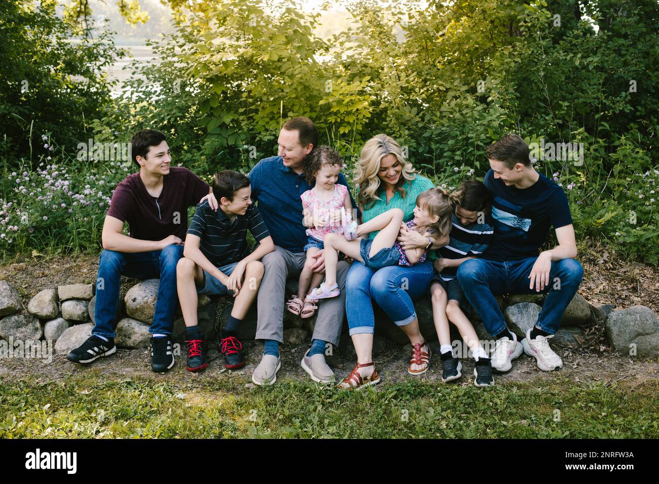 Eine Familiengruppe lacht zusammen im grünen Wald mit vielen Kindern Stockfoto