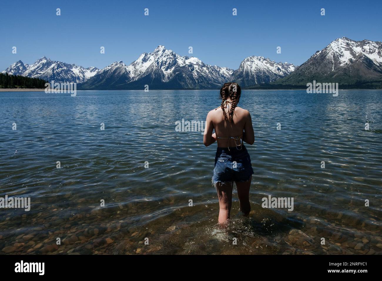 Ein Mädchen, das an einem sonnigen Tag in den See geht Stockfoto