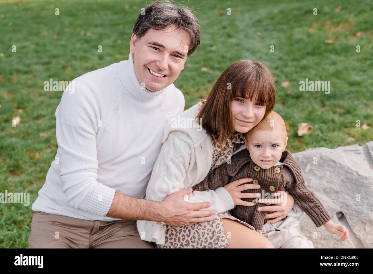 Junger italienischer Mann, kleiner Junge und Tochter im Teenageralter, die sich draußen umarmen Stockfoto