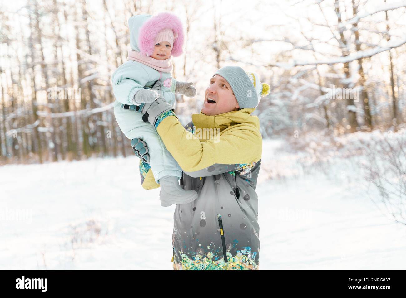 Vater und eine einjährige Tochter machen einen Spaziergang in einem verschneiten Park Stockfoto