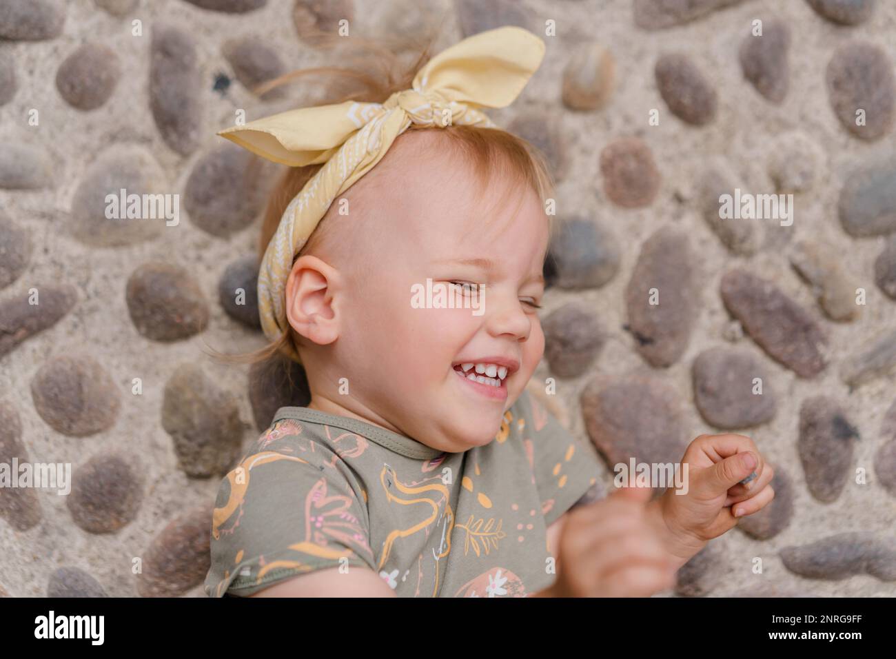 Das weiße Mädchen lügt und lacht auf den Pflastersteinen im Stockfoto