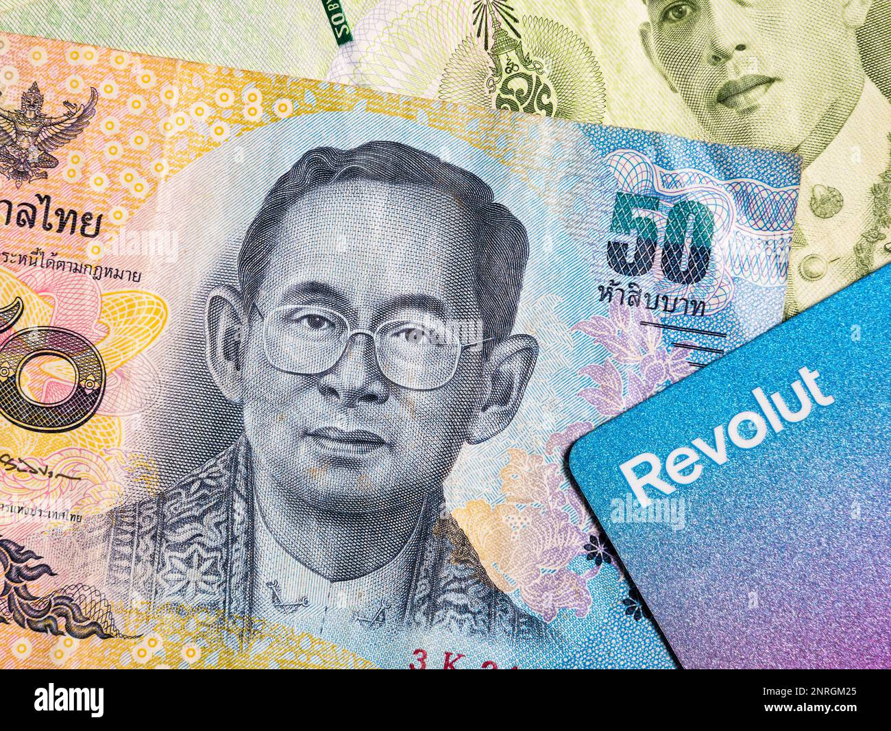 Makrodetails mit einer thailändischen 50-Baht-Banknote und einer revolut-Debit- oder Kreditkarte. Der Baht ist die offizielle Währung Thailands Stockfoto