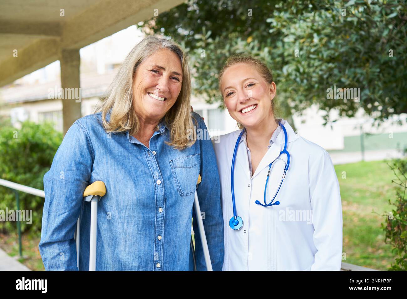 Porträt einer glücklichen Arztin im Garten mit einer behinderten Seniorin Stockfoto
