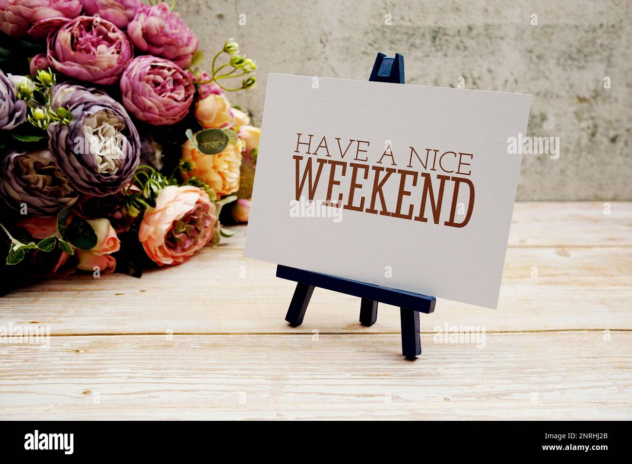 Haben Sie einen schönen Wochenendtext auf Papierkarte mit Blumenstrauß auf Holzhintergrund Stockfoto