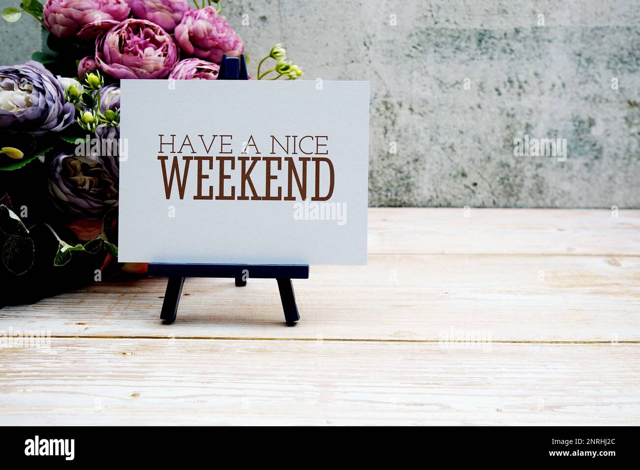 Haben Sie einen schönen Wochenendtext auf Papierkarte mit Blumenstrauß auf Holzhintergrund Stockfoto