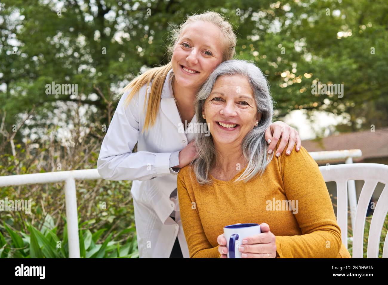 Porträt einer glücklichen Ärztin mit Seniorin im Garten des Pflegeheims Stockfoto