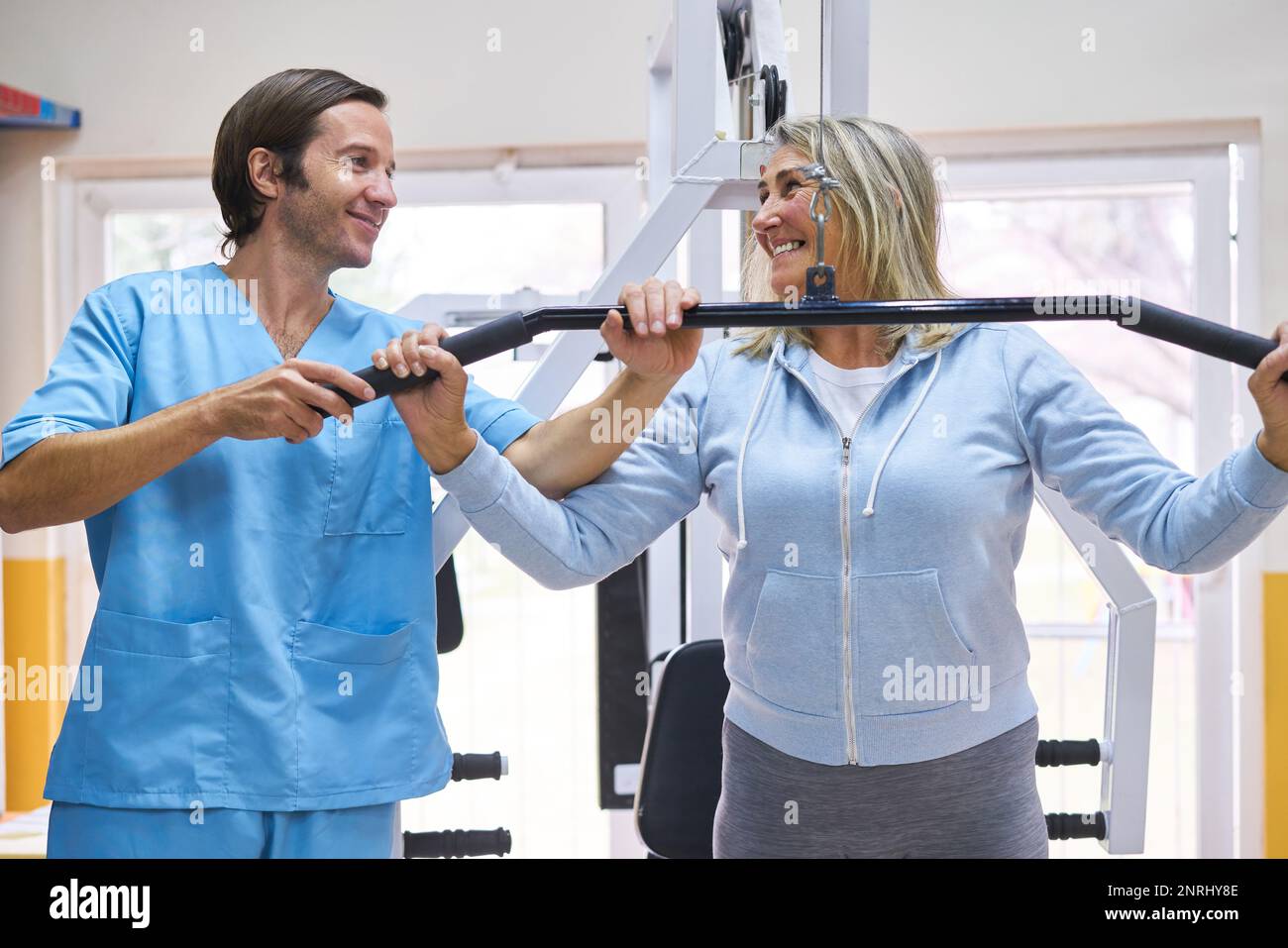Lächelnde Seniorin mit männlichem Physiotherapeuten, der die Ausbildung im Reha-Zentrum erklärt Stockfoto