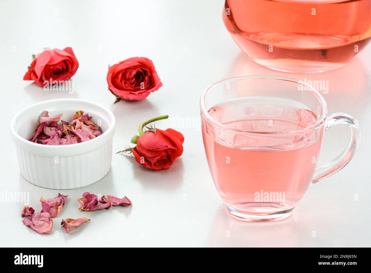 Rose Tea in einem Glasbecher mit getrockneten Rosen im Hintergrund Stockfoto
