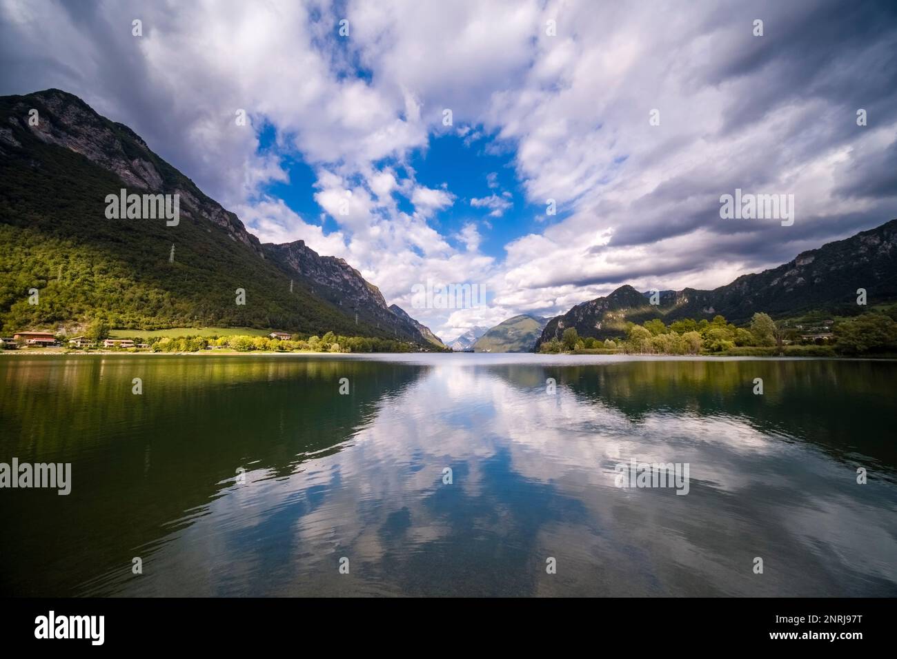 Landschaft mit Bergen, Berghängen, Wäldern und Wolken, die sich auf der Oberfläche des Sees Lago d'Idro spiegeln. Stockfoto