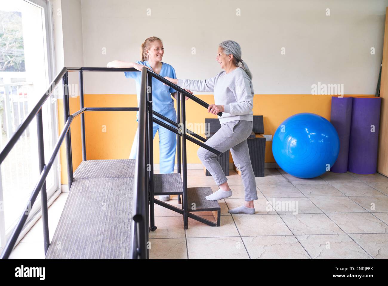 Lächelnde Physiotherapeutin als Assistentin der Seniorin in der Bewegungstherapie im Rehabilitationszentrum Stockfoto