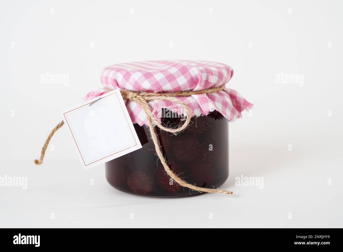 Glas hausgemachter Erdbeermarmelade mit leerem Etikett isoliert auf weißem Hintergrund Stockfoto