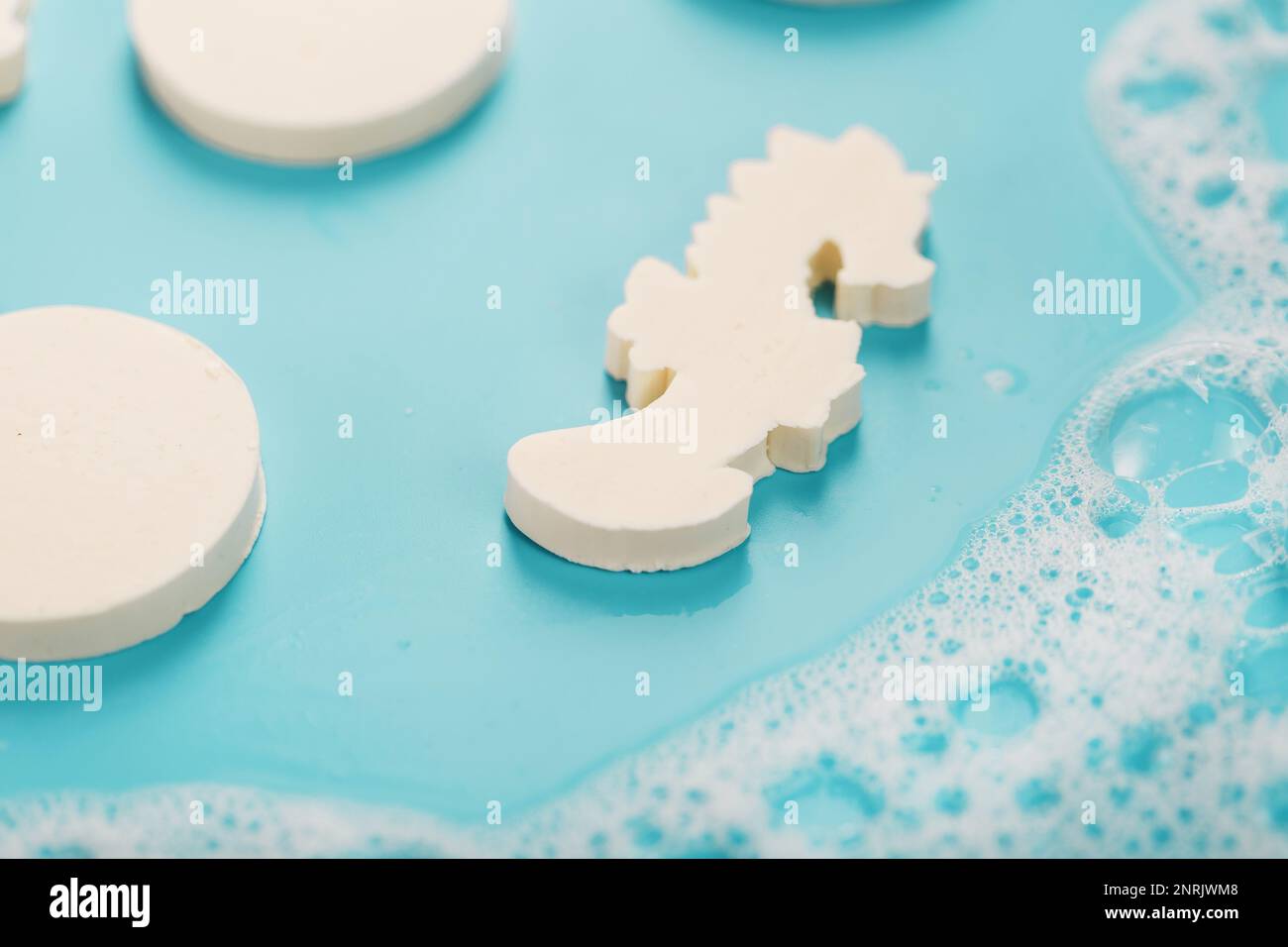 Seife in Form eines Seepferdchens und Kreise mit Schaumstoff auf blauem Hintergrund Stockfoto