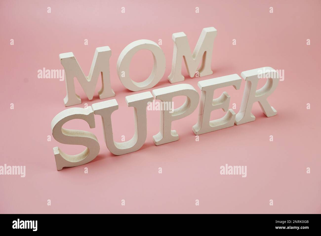 Buchstaben des Super-Mom-Wortes auf pinkfarbenem Hintergrund Stockfoto
