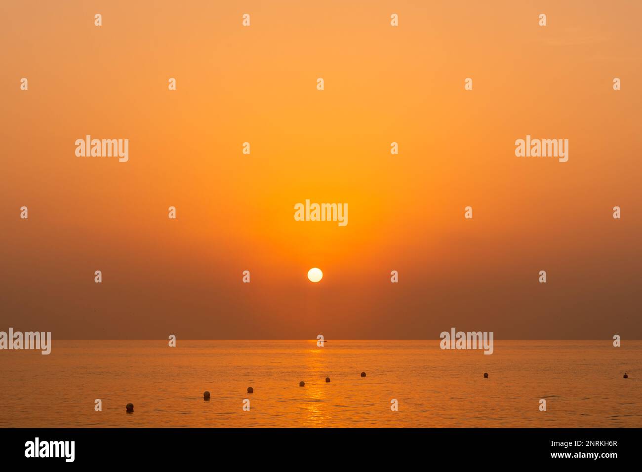 Heller und wunderschöner Sonnenaufgang mit einem orangefarbenen Licht am Strand. Stockfoto