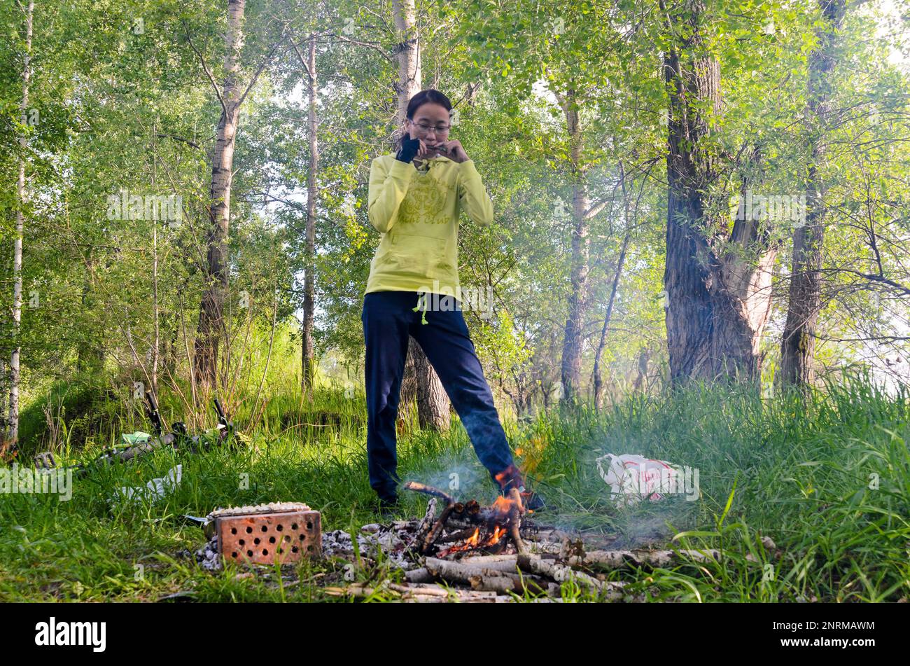 Yakut-Mädchen, die bei einem Waldbrand Khomus spielt Stockfoto