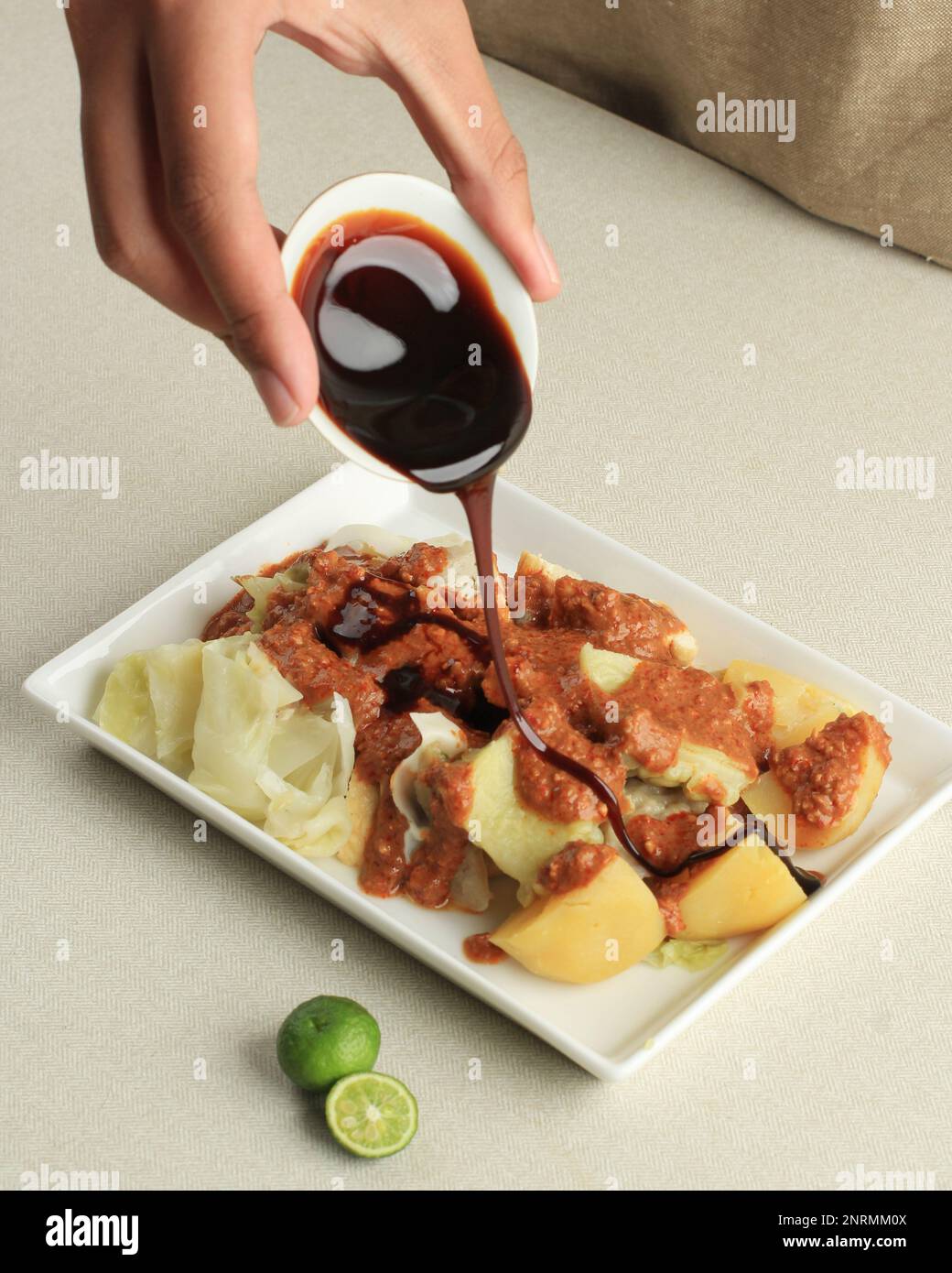 Gieße süße Sojasauce Kecap zu Siomay Bandung, gedämpfte Fischklöße mit Gemüse und Erdnusssoße Stockfoto