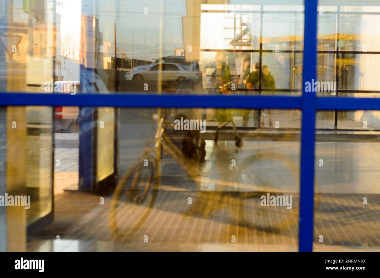 Abstraktes Foto der Reflexion von Fahrrädern und Menschen im Schaufenster eines Einkaufszentrums bei Sonnenuntergang in Russland. Stockfoto