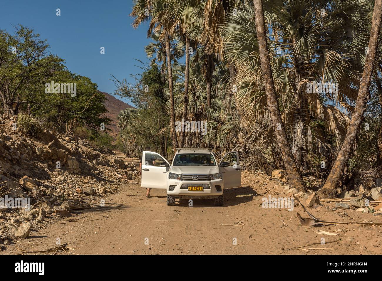 Auto auf einer staubigen Schotterstraße entlang des Flusses Kunene im Norden Namibias Stockfoto